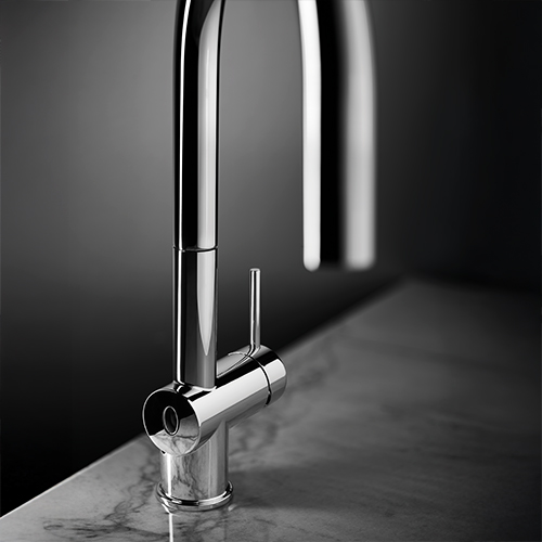 Focus sur un robinet de cuisine chrome dans une cuisine grise.